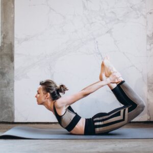 A woman performing the bow pose in a serene indoor setting, emphasizing fitness and mindfulness.