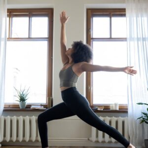 Woman practicing yoga in a well-lit modern home setting, promoting wellness and tranquility.