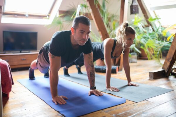Man and woman doing yoga together at home, emphasizing fitness and healthy lifestyle.